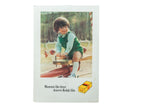 Vintage 1970s Kodak film advertisement featuring a child in green on a playground seesaw.