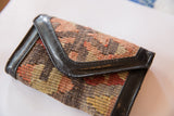 Textured geometric pattern of a vintage Kilim rug fragment wallet with dark faux leather trim.