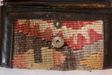 Vintage Kilim wallet fragment showing geometric pattern, warm earth tones, and snap patina.