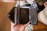 Open vintage wallet showing dark faux leather interior, zipper, and patterned lining.