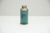 Close-up of antique dental tin, featuring turquoise body and dark blue woman graphic.