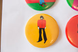 Bright yellow Beatles pin with character in a red jacket.