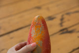 Chipped red and orange paint, revealing a crack on the vintage chili pepper bank.