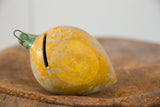 Vintage Mexican folk art mango piggy bank, its yellow paint extensively chipped.