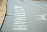 White 'KATONAH' lettering and deer graphic on a light grey eco-friendly blanket.