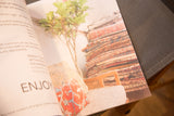 An open page of the Old New House coloring book with text and a photo of stacked vintage rugs.