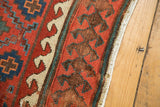 Close-up of antique Caucasian rug's vibrant cherry red, ivory wave, and charcoal plant borders.