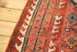 Antique Caucasian rug: cherry red lattice, teal plant motifs, ivory wave border, and wear.