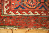 Red reciprocating wave border, exposed foundation, and tattered edge of antique Caucasian rug.