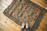 Textured corner of antique Caucasian rug with banded starbursts, floral borders, and soft fringe.