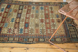 Geometric banded starburst pattern on an Antique Caucasian rug in madder red, ivory, and sky blue.