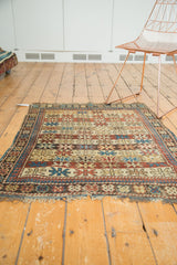 Antique Caucasian rug corner with geometric starburst motifs and tattered fringe.