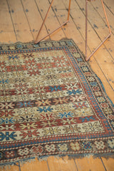 Antique Caucasian rug corner: banded starburst motifs, detailed borders, tattered end, madder red and ivory.