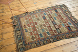 Aged fringe and geometric border on an antique Caucasian rug corner, featuring starburst motifs.