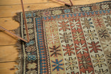 Antique Caucasian rug corner with starburst motifs, madder red, sky blue, and aged fringe.