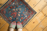 Tattered edge of vintage Lilihan rug showing indigo blue and cranberry floral palmettes.