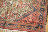 Antique bag face rug corner: ivory field, colorful paisley, and stepped border.