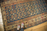 Kurdish rug corner, navy field with bronze shrub and pinwheel motifs, and geometric borders.