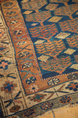 Vintage Kurdish rug with navy blue field, bronze shrub motifs, and antique ivory patterned border.