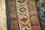 Detail of hand-knotted Kurdish rug showing navy, bronze, beige geometric patterns, pinwheels, and light tatter.