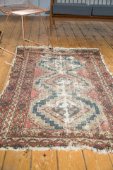 Close view of vintage Hamadan rug's tattered fringe, stepped contours, and floral border.