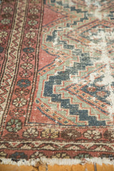 Worn pile of vintage Hamadan rug, raspberry and indigo geometric patterns, tattered fringe.