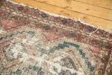 Tattered edge of vintage Hamadan rug with visible foundation, oxidized raspberry, and indigo patterns.