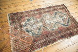 Exposed foundation and tattered edges on a vintage Hamadan rug's floral border.