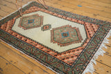Corner of Vintage Ardebil rug with hand-knotted fringe, sage green, and apricot geometric borders.
