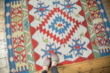Vintage Turkish Kilim rug's left border with blue oval, saffron vine, and green wave motifs.