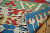Folded Turkish Kilim rug corner, revealing ivory fringe and geometric patterns on both sides.