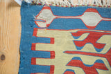 Detail of hand-woven Turkish Kilim flatweave, showcasing serrated red, blue, and ivory geometric patterns.
