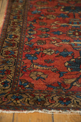 Corner of vintage Persian Lilihan rug, brick red field, teal floral border, lightly tattered fringe.