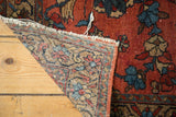 Corner of a vintage Persian Lilihan rug, showing hand-knotted reverse and brick red pile with light tatter.