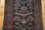 Mehreban rug detail: asymmetric unidirectional reptile and floral motifs in indigo, bronze, sky blue.