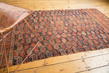 Antique Afshar fragment featuring repeating boteh, tattered edges, and rich indigo, madder tones.