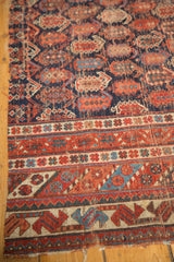 Geometric tribal borders and repeating boteh pattern on a worn antique Afshar rug fragment.