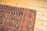 Fragmented antique Afshar rug corner showing repeating boteh motif and geometric borders in madder and indigo.