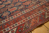 Persian Afshar rug fragment's hand knotted texture, geometric border, boteh motifs, and tattered edge.