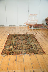 Hamadan rug corner, diamond motif, blue wave border, dusty apricot, and tattered end.
