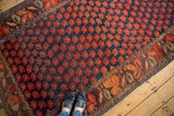 Antique Karabagh rug detail: indigo blue field with staggered red floral pattern, featuring abrashes and ornate border.