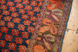Karabagh carpet detail: indigo field with repeating red floral motifs and intricate aubergine, orange border.