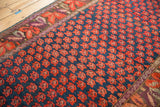 Antique Karabagh carpet: indigo field with staggered tomato red florals and abrash, complex border.