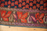 Antique Karabagh rug detail: indigo floral field, scrolling guard border, and vibrant aubergine palmette motifs with abrashes.