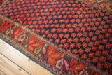Antique Karabagh carpet: repeating red floral motif on indigo field, with aubergine border.