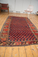 Antique Karabagh carpet, repeating red floral motifs in a lattice outline on deep indigo.