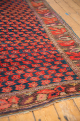 Antique Karabagh carpet detail: full even pile, repeating red floral motifs on indigo, aubergine and celadon border.