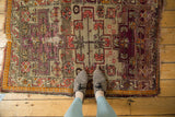 Antique Caucasian rug's geometric vinery, aubergine, and tangerine pattern with visible storied character.
