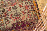 Geometric vinery and Laleh Abassi border on antique Caucasian rug, with aubergine and tangerine tones.