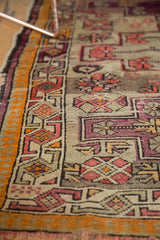 Antique Caucasian rug: tangerine outer border and aubergine geometric vinery with visible foundation.